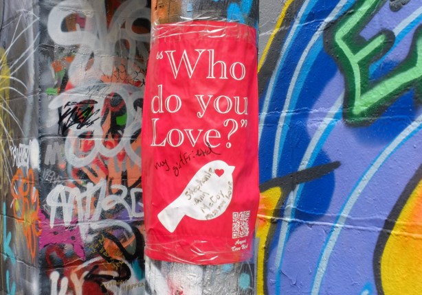 graffit, red background with a little white bird, with text who do you love?