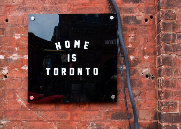 black and white sign on brick wall that says home is toronto
