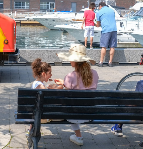 a mother and daughter sitting on a bench eating ice cream