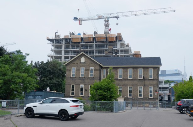 white car parked in frontof an old school building, brick, two storey, with condo development going on behind, is now Inglenook community school. 
