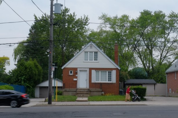 a woman pushes a stroller past a small house on Marlee Ave