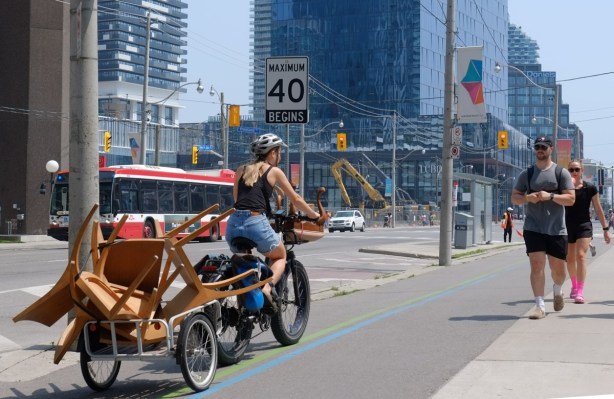 woman on bicycle with a trailer full of furniture