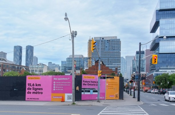 pink signs on hoardings around construction site for Ontario Line