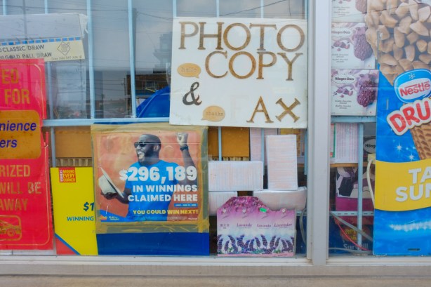 signs in the window of a convenience store, photocopy, drumstick ice cream advert, winning tickets for lottery sold here, 