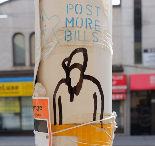 graffiti on a TTC bus stop pole, that says post more bills, with a rough drawing of a person