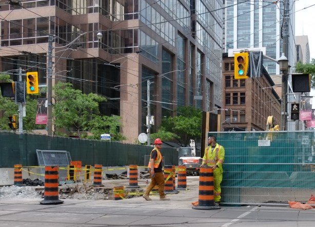 two workmen at blocked Queen Street at church, Ontario Line metrolinx construction