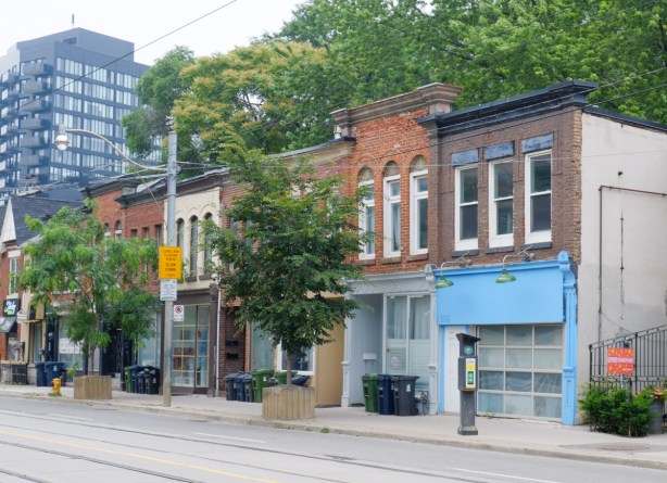 a row of two storey brick store fronts, one has a lot of light blue trim, 