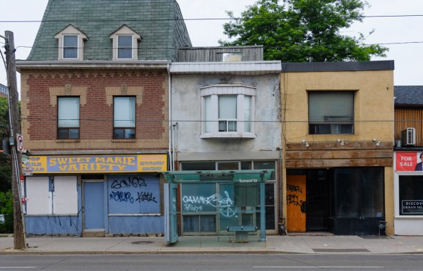 row of three old buildings, two storey store fronts, all empty. Sweet Marie convenience store on the left, at corner of Queen and Sumach