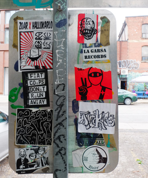 many stickers on the back of a traffic sign