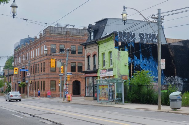 south side of Queen st east, looking east towards Charry Street, vacant lot, then a bright green building, 