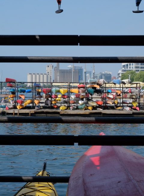 looking through a rack of upside down kayaks towards the rest of the waterfront