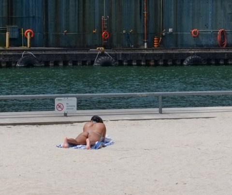 woman in thong bikini laying prone, sun tanning, sugar beach