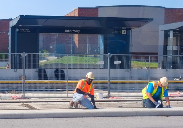 two workmen working on new tracks along finch ave lrt route