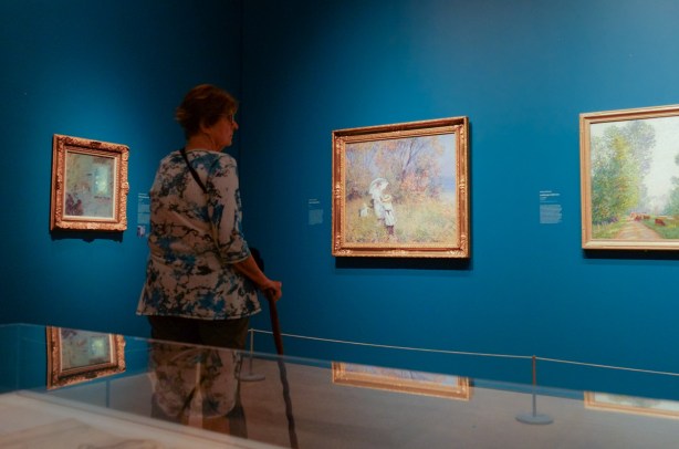 woman with a cane looking at paintings in a gallery