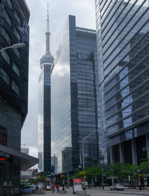 CN Tower peaking out from behind galss buildings on Bremner, reflections in the glass too 