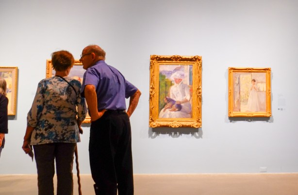 an older couple looking at paintings in a gallery