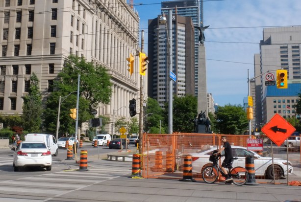orange fence around part of University Ave., a cyclist approaches the intersection