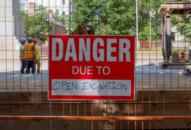 red and white danger due to open excavation sign on a wire fence