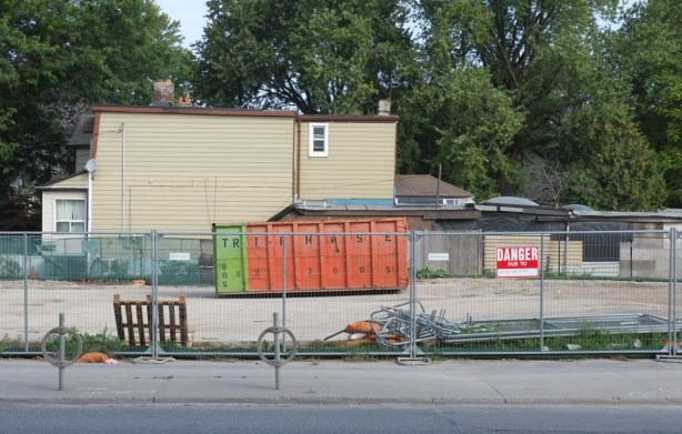 an orange bin sits in a vacant lot where a building has just been demolished
