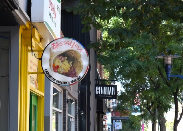 signs for stores on Queen East including Blessed Love Caribbean