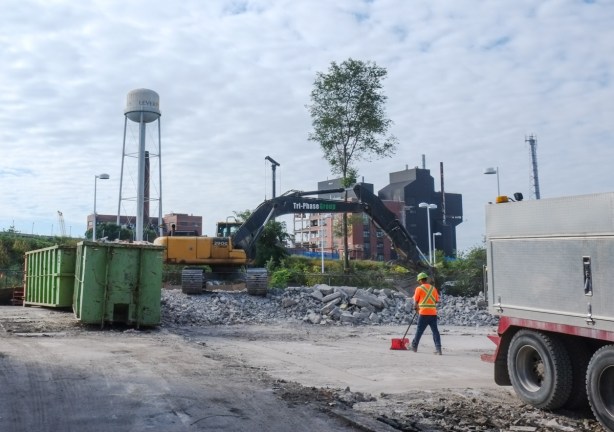 construction site south of Eastern Ave., west of the train tracks, a man with a red shovel is clearing a now vacant lot 