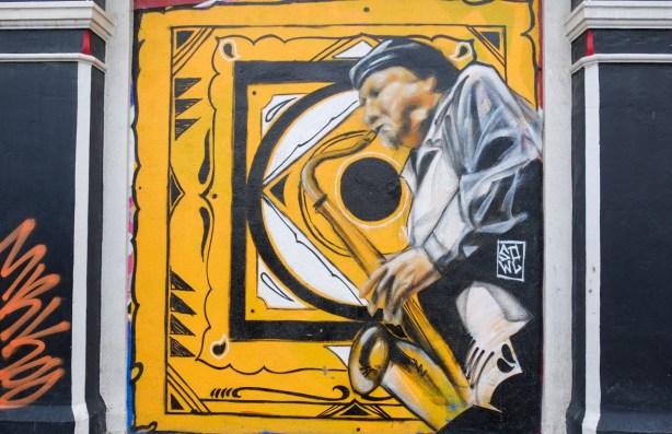 street art painting of a saxophone player on yellow background, at the Duke tavern