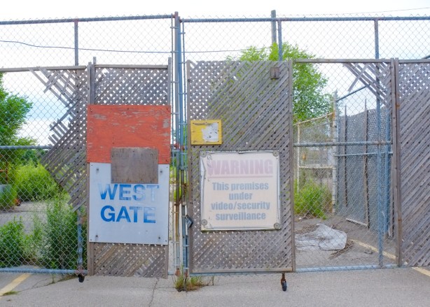 faded warning signs on a locked gate and chainlink fence