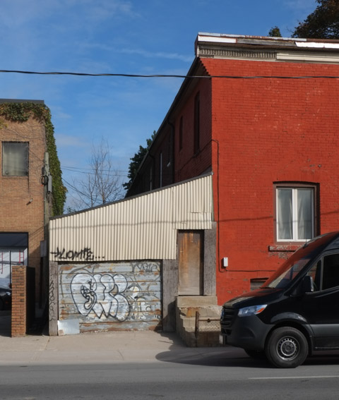 back of a house that has been painted orange, an old garage with graffiti on the door