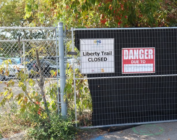 2 signs on a fence, one is a danger due to demolition and the other says liberty trail is closed, Second sign was posted by ontario transit group