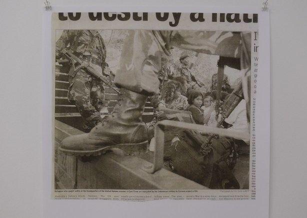 newspaper picture of refugees in East Timor, large boot of a soldier in the foreground