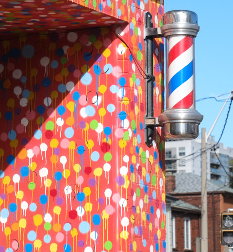 red, white, and blue, barber pole on a wall painted orange with primary colour dots, 