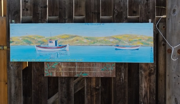 my blue world, a painting on a wood fence, of two boats in the water, 