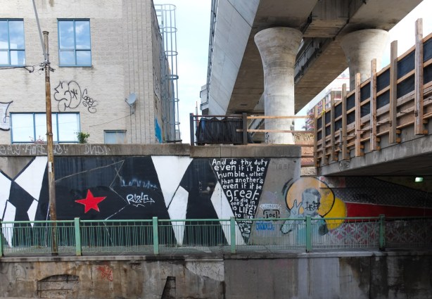 mural on underpass wall, construction on railway track above, along with elevated tracks being built above that 