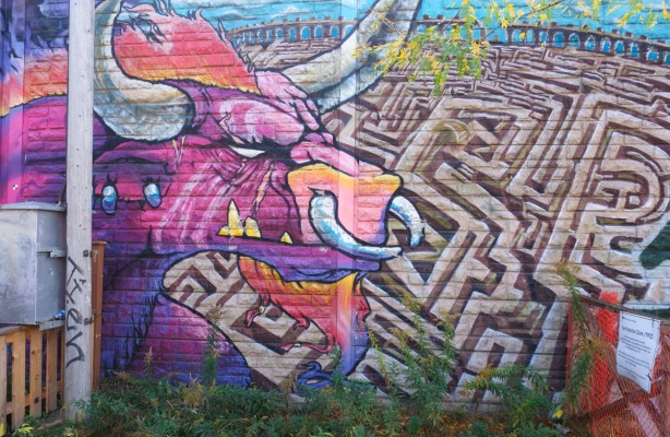 mural, bull in pinks and purples, 2 large horns, ring through nose, in front of a maze, like minotaur