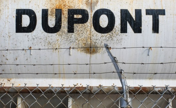 the word dupont written in upper case block letters, black, on an old metal truck, barbed wire in front of it 