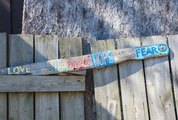 words written in many colours across a board on a wood fence in an alley, a quote from Jack Layton that says 
