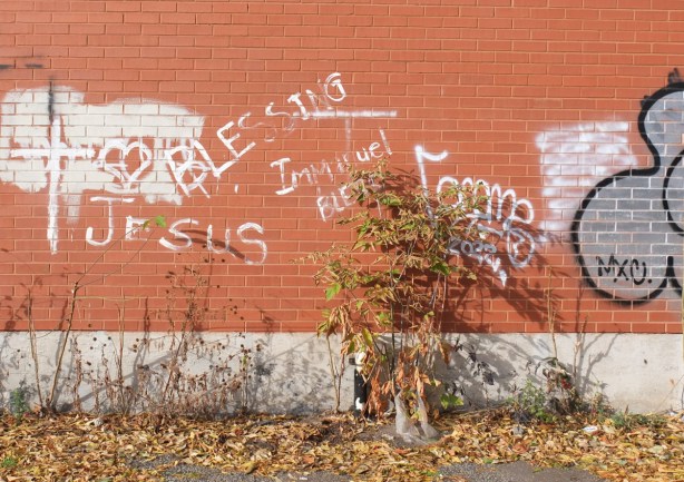 white words written on a red brick wall Jesus, blesses, immanuel, also a white cross