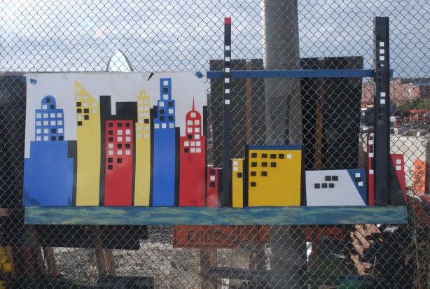painted streetscene on fence with construction behind