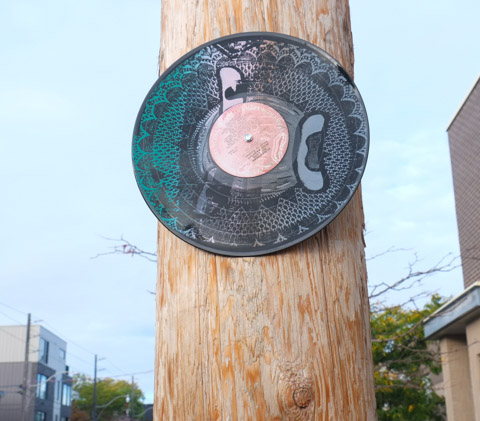 graffiti on a wood utility pole made from a vinyl LP record 