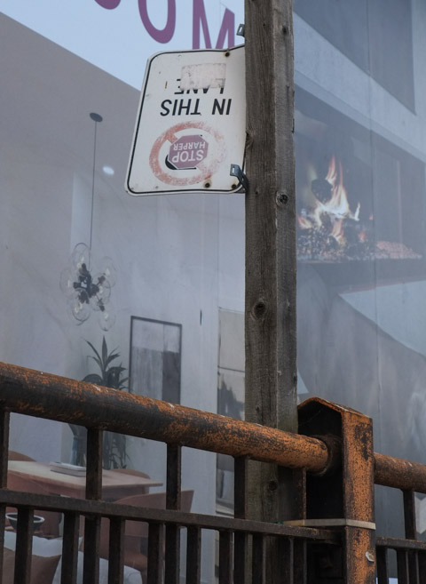 old stop harper sticker on a no parking sign, that is upside down, 