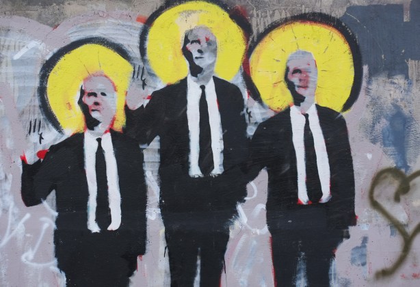part of Suitman mural on Dupont Street, 3 men in black suits, white shirts, and black ties, standing together. they all have large yellow halos, or circle auras around their heads
