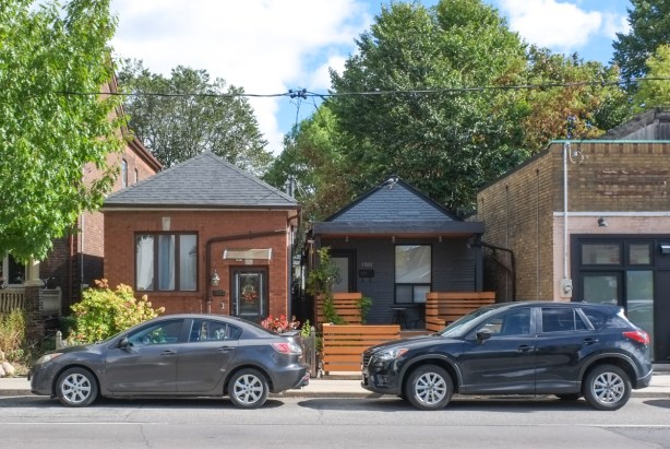 two narrow bungalows side by side, 2 dark cars parked on street in front of the houses