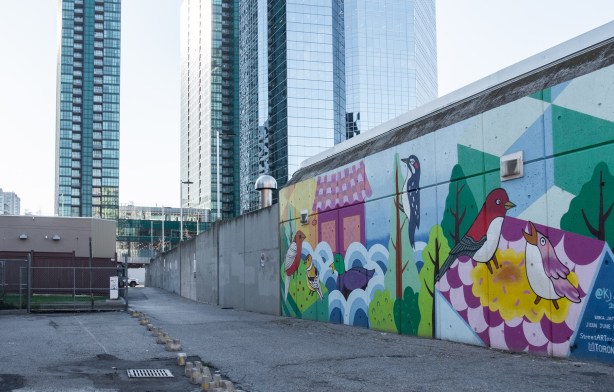 wall at Sheppard station TTC bus loop, mural of birds by June Kim, with Emerald condo development in the background