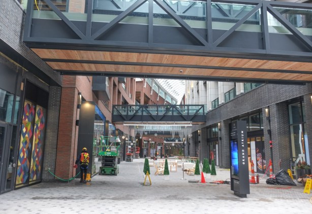 covered walkways overhead, lower level of the well, small artifical christmas trees, workmen working, glass ceiling,