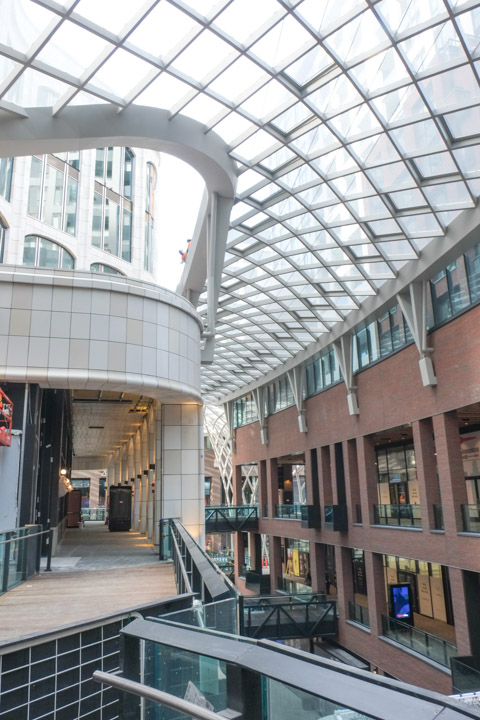 interior view of the middle of the well, three storeys of brick mall with curved glass ceiling above