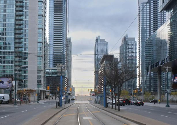standing on streetcar tracks TTC and looking south on Spadina, at Front street, with glass tower condos on both sides
