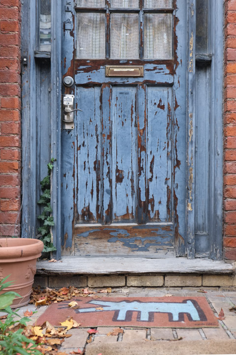 old blue wood door on brick house, stone step, welcome mat with keith herrig image on it 