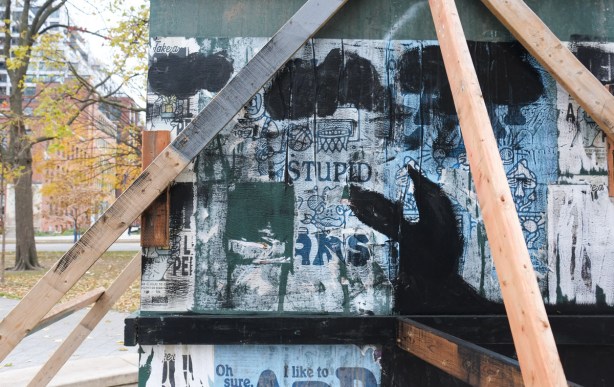 close up of paper paste ups on plywood covering sculpture in the middle of a dry fountain in clarence park 