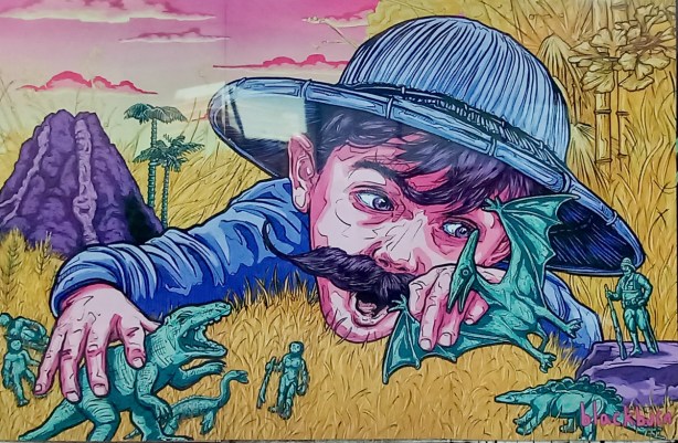 boy in blue pith helmet lying onthe grass playing with toy dinosaurs, painting in a mural by jeff blackburn