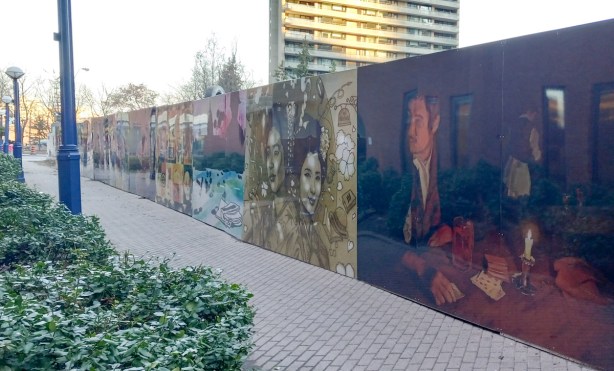 pathway behind library, with hoardings on right side, painted with images with sherlock holmes theme